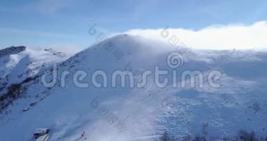 轨道航空飞越冬季雪山山顶滑雪道度假村与滑雪者滑雪。 晴天，雾蒙蒙的云.. 雾升起了